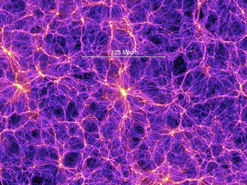 Nesta imagem, proveniente de uma das melhores simulações da formação das grandes estruturas do universo, são claramente visíveis filamentos de matéria escura que contêm superaglomerados de galáxias. Observa-se também a presença de grandes vazios, por vezes designados por «vazios cósmicos» (cosmic voids, em inglês). A barra branca indica a escala de distâncias em megaparsecs, corrigida pelo fator h associado à constante de Hubble. Estima-se que h se situe entre 0,65 e 0,70, sendo a melhor estimativa...